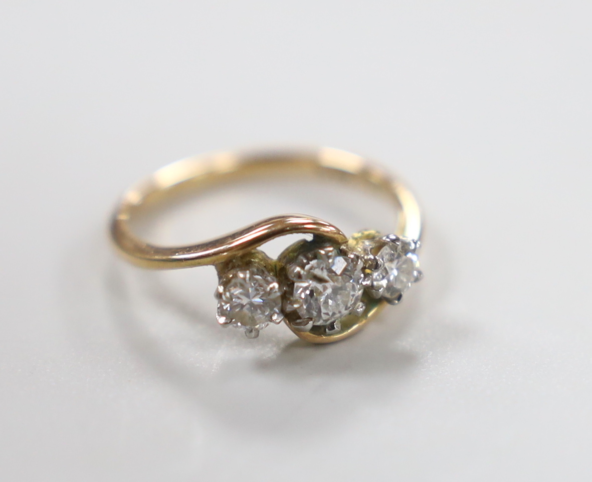 A 14k and three stone diamond set crossover ring, size H, gross weight 2 grams.